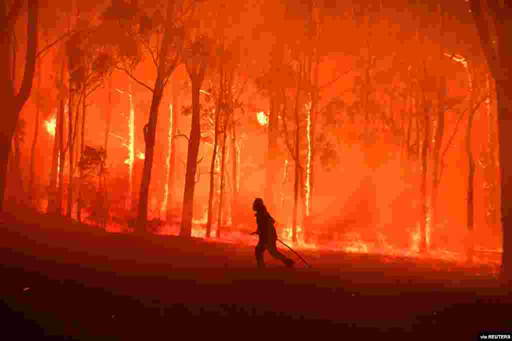 An NSW Fire and Rescue officer protects the Colo Heights Public School from being affected by the Gospers Mountain Fire near Colo Heights, southwest of Sydney, Australia. (Credit: AAP Image/Dean Lewins)