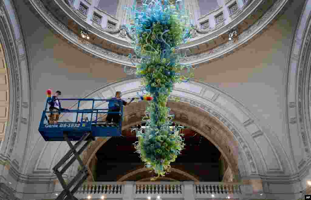 Museum technicians clean one of the V&amp;A&#39;s most iconic and largest pieces—a 27-foot glass chandelier comprising 1,300 exquisite blue and green glass elements, which hangs in the museum&#39;s Grand Entrance in London, Aug. 4, 2020.