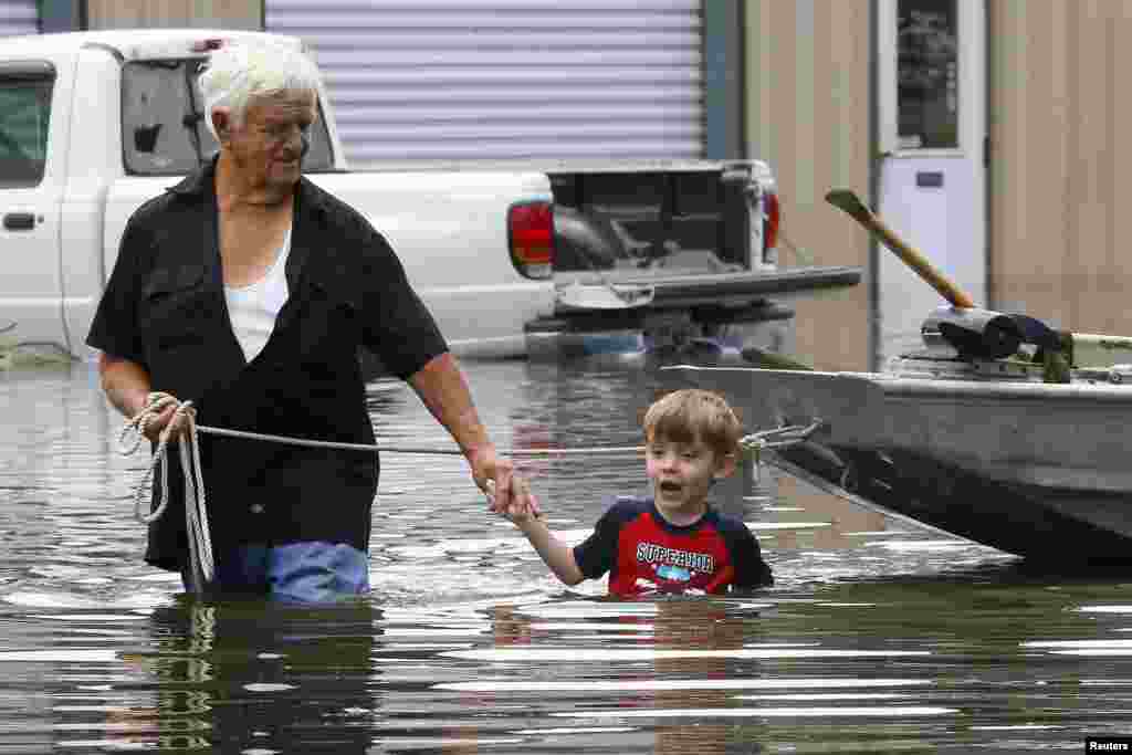 Richard Rossi and his 4 year old great grandson Justice wade through water in search of higher ground after their home took in water in St. Amant, Louisiana.