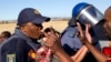 Police attempt to stop workers from marching toward mine before memorial service near Lonmin platinum mine, Marikana, South Africa, Aug. 16, 2013.