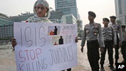 Anggota kepolisian tengah mengamati seorang pria yang membentangkan poster menentang kelompok militan ISIS dalam sebuah aksi protes di Jakarta (15/9).