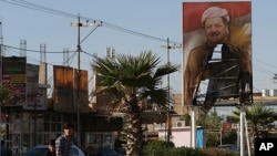 Poster Presiden Wilayah Otonomi Kurdi, Massoud Barzani, tampak terbakar di depan gedung pasukan keamanan Kurdi yang ditelantarkan di Kirkuk, Irak, 19 Oktober 2017.