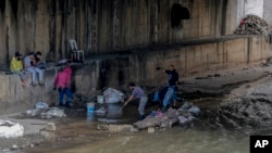 Men sift through a sewer for valuables along the foreshore of the Abou Ali River, in the northern city of Tripoli, Lebanon, May 5, 2020.