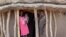 FILE - In this May 2, 2018, photo children stand in the doorway of their home as they watch their mother prepare food she received from an aerial food drop by the World Food Program in the town of Kandak, South Sudan. 