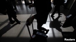 Passengers cast shadows as they walk along a terminal at Los Angeles International Airport in Los Angeles, California, March 4, 2013. 