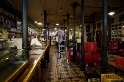 FILE - Martin Guerrero, general director of tavern-restaurant and flamenco tablao Casa Patas, climbs a ladder to change a light bulb at Casa Patas, which is closed due to the coronavirus lockdown, in Madrid, Spain, June 2, 2020.
