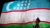 FILE - A soldier stands in front of the national flag of Uzbekistan, in Tashkent, Aug. 31, 2012.