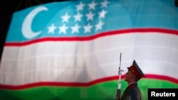 FILE - A soldier stands in front of the national flag of Uzbekistan, in Tashkent, Aug. 31, 2012.