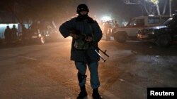 Police officer stands guard after arriving at site of Taliban suicide attack, Kabul, Nov. 27, 2014.