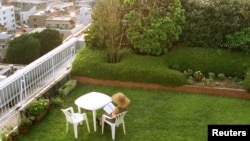 Seorang perempuan membaca buku di taman di atas atap gedung apartemen di Tokyo. (Foto: Dok)