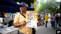 An activist of the opposition Justice First party holds a poster showing how to vote in congressional elections in Caracas, Venezuela, Nov. 26, 2015 — a day after Luis Diaz, a leader of the opposition Democratic Action party, was shot and killed.