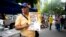 An activist of the opposition Justice First party holds a poster showing how to vote in congressional elections in Caracas, Venezuela, Nov. 26, 2015 — a day after Luis Diaz, a leader of the opposition Democratic Action party, was shot and killed.