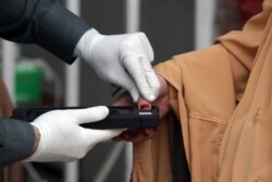 A woman gets her thumb verification to receive cash from a program introduced by the government for vulnerable families due to the spread coronavirus disease in Peshawar, Pakistan, April 9, 2020.