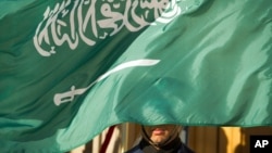 FILE - An honor guard member is covered by the flag of Saudi Arabia, in Washington, March 22, 2018. In the past 24 hours the kingdom reportedly carried out a record number of executions.
