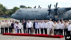 American and Philippine government officials pose before the three church bells seized by American troops as war trophies more than a century ago, as they were returned to the Philippines in suburban Pasay city southeast of Manila, Philippines, Dec. 11, 2018.