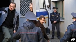 Activists, detained at a rally, are escorted by police officers as they leave a police van for a court hearing in Minsk, Belarus, March 27, 2017. 