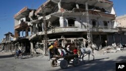 FILE - The remains of buildings line a street that was damaged the previous summer during fighting between U.S.-backed Syrian Democratic Forces fighters and Islamic State militants, in Raqqa, Syria, April 5, 2018.