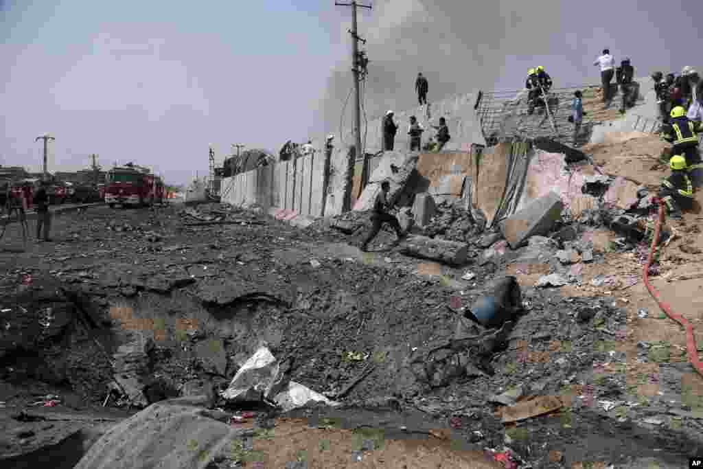 Afghan firefighters work at the site of Monday&#39;s suicide bomb attack in Kabul. The attack occurred near the the Green Village, home to several international organizations and guesthouses.