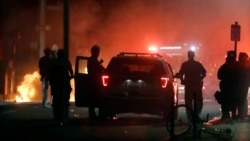 A police car burns, left rear, after being set on fire in Boston, Sunday, May 31, 2020, following a march and gathering to protest the death of George Floyd, who died after being restrained by Minneapolis police officers on May 25.