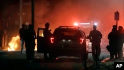 A police car burns, left rear, after being set on fire in Boston, May 31, 2020, following a march and gathering to protest the death of George Floyd, who died after being restrained by Minneapolis police officers on May 25. 