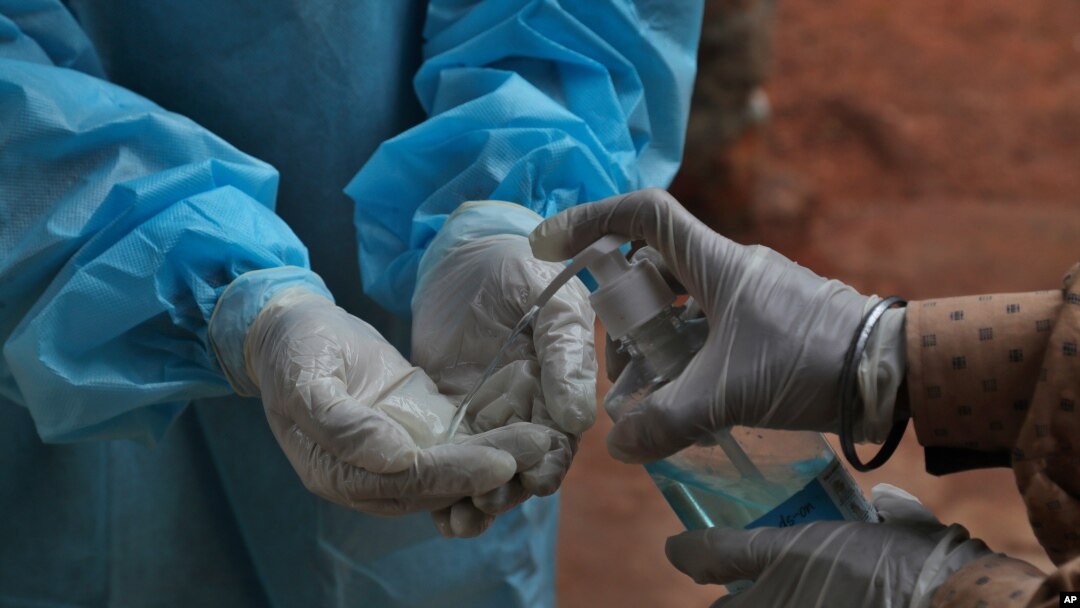 Seorang petugas kesehatan tampak membersihkan tangannya setelah mengambil sampel tes usap (swab test) dari seorang pasien di pusat tes COVID-19 di Hyderabad, India, pada 11 Oktober 2020. (Foto: AP/Mahesh Kumar A.)