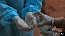 Seorang petugas kesehatan tampak membersihkan tangannya setelah mengambil sampel tes usap (swab test) dari seorang pasien di pusat tes COVID-19 di Hyderabad, India, pada 11 Oktober 2020. (Foto: AP/Mahesh Kumar A.)