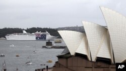 A cruise ship hangs a large national flag in celebration of Australia Day, in Sydney Harbour behind the Opera House in Sydney, Jan. 26, 2012.