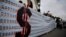 FILE - Demonstrators hold a banner made from three thousand two-bolivar-bills, that is equivalent approximately to $1 according to the black market exchange rate, in Caracas, Venezuela, June 10, 2017. 
