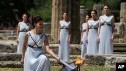 Une danseuse allume la flamme olympique dans l'Ancien Olympia, Grèce, jeudi 21 avril, 2016.