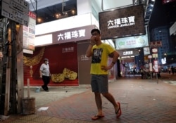 A pedestrian covers his nose from the tear gas as he walks past a jewelry shop during an anti-government protest in Hong Kong, China, Oct. 27, 2019.