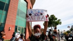 File- A woman holds a sign addressing ANTIFA at a protest in Los Angeles on Monday, June 1, 2020, over the death of George Floyd, who died May 25 in Minneapolis.
