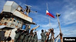 Anggota Marinir yang berlayar dengan kapal BRP Sierra Madre, ikut mengibarkan bendera di kapal yang terdampar di Dangkalan Thomas II yang merupakan bagian dari kepulauan Spratly yang menjadi sengkera di Lautan China Selatan (29/3).