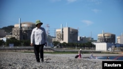 FILE - Hwang Bun-hee takes a walk on a seashore as Wolseong Nuclear Power Plant is seen in the background in Gyeongju, South Korea, Aug. 21, 2022. South Korea approved the construction of two nuclear reactors on its east coast on Sept. 12, 2024.