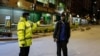 FILE - A Kenyan police officer stops a man who was heading home past the start of the daily dusk-to-dawn curfew in the Eastleigh area of Nairobi, Kenya.