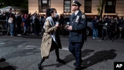 A person engages with a New York City police official as he, along with other officers, move to clear a main gate at Columbia University in New York on April 30, 2024, as authorities cleared parts of the campus of protesters after a building was taken over by activists.