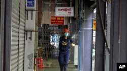 ရန်ကုန်မြို့ Scott ဈေးမှာ ပိတ်ထားရတဲ့ ဆိုင်တွေအနီး ပိုးသတ်ဆေးဖျန်းနေတဲ့ ဝန်ထမ်း တဦး (မတ် ၃၀၊ ၂၀၂၀)