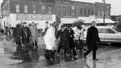 Dr. Martin Luther King Jr. hops over a puddle as it rains in Selma, Alabama. He led hundreds of African Americans to the courthouse in a voter registration drive, March 1, 1965.