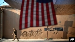 2011年9月11日一名美軍走過在阿富汗庫納爾省“前哨作戰基地”為紀念9/11襲擊十週年而懸掛的美國國旗。