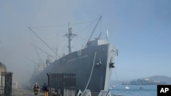 Fire officials stand in front of the SS Jeremiah O'Brien after a fire broke out before dawn at Fisherman's Wharf in San Francisco, May 23, 2020. A warehouse was destroyed.