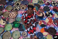 FILE—Anasitasia Nyirabashyitsi, 54, weaves a grass and thread bowl outside her home at Mybo reconciliation village in Nyamata, Rwanda, April 5, 2024.