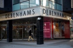 A man wearing a face mask walks past the Debenhams flagship department store on Oxford Street, during the second coronavirus lockdown in London, Dec. 1, 2020.