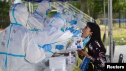 A medical worker in a protective suit conducts a nucleic acid test for a resident, following a new outbreak of the coronavirus disease (COVID-19) in Beijing, China, June 20, 2020.