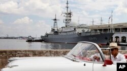 An American classic car passes in front of the Russian spy ship The Viktor Leonov SSV-175 docked in Havana's harbor, Feb. 27, 2014.