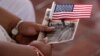 A woman holds a US flag before she became US citizen during a special naturalization ceremony in honor of Citizenship Day and Constitution day Ellis Island in New York on September 16, 2016.