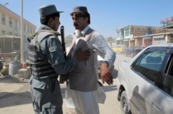 FILE - An Afghan policeman body checks a man in Khost, Afghanistan, Oct. 2, 2011. Security measures are tight after the capture of Haji Mali Khan, a senior Haqqani leader inside Afghanistan.