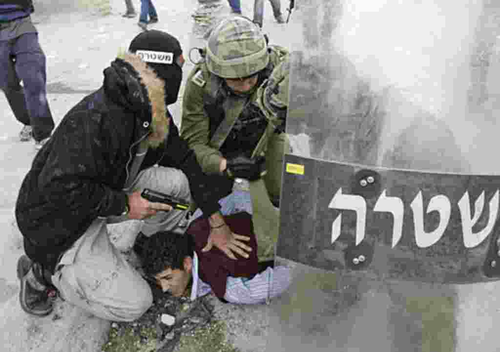 A plainclothes Israeli police officer and soldiers detain a Palestinian protestor during clashes near the Qalandiya checkpoint between Ramallah and Jerusalem, Sunday, May 15, 2011