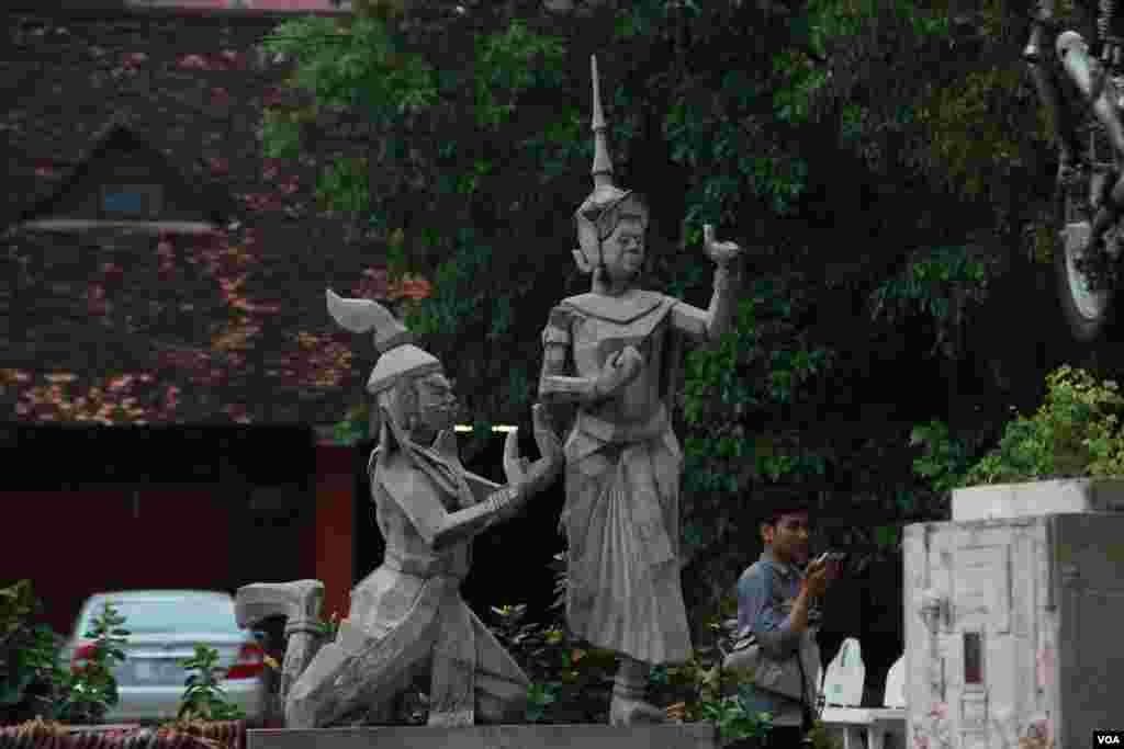 A man walks pass by a statue of Moni Mekhala, goddess of the seas, and Ream Eyso, storm demon, inside Royal University of Fine Arts on May 28, 2015. (Nov Povleakhena/VOA Khmer)