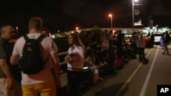 In this image from video taken Feb. 2, 2019, travelers stay outside the international airport after an evacuation in Brisbane, Australia. A man who falsely claimed to have a bomb forced the evacuation of the evacuation of the airport for more than two hours, police said Sunday. 