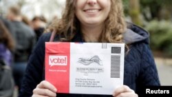 ARCHIVO - Una mujer en Seattle, Washington, muestra el sobre donde porta su boleta de voto por correo durante las elecciones del candidato presidencial por el partido demócrata. Febrero 22, 2020.