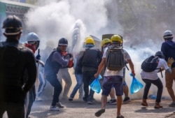 Anti-coup protesters use fire extinguishers to reduce the impact of teargas fired by riot policemen in Yangon, Myanmar, March 9, 2021.